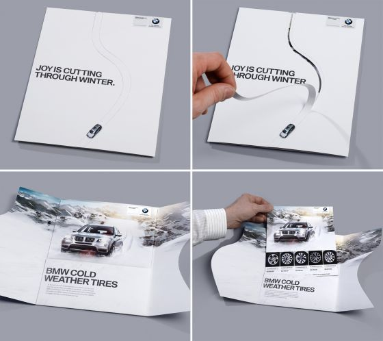 Interactive BMW direct mail brochure for cold weather tires, showing a car driving through snow. The folded mailer opens to reveal a winter driving scene and tire options.